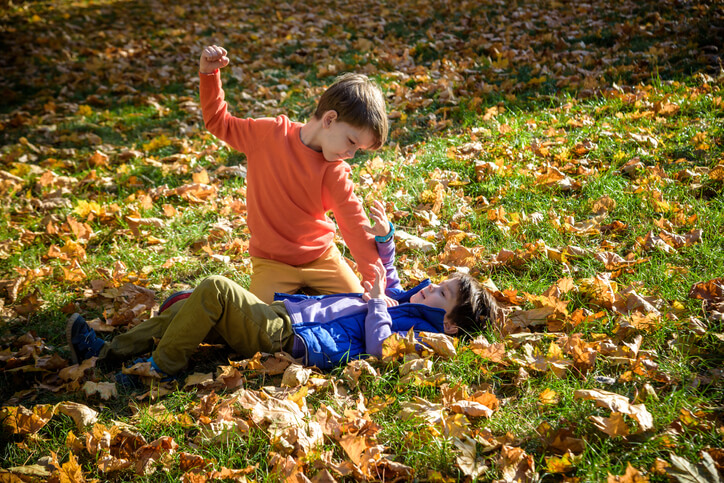 Two boys fighting outdoors.