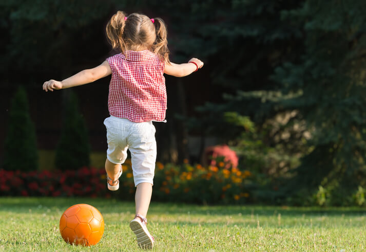 a young girl kicking a ball in the park