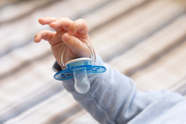 Child's hand holding a pacifier