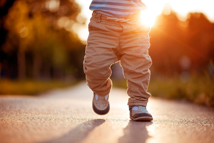 close up of a young boys legs as he is walking down a sidewalk