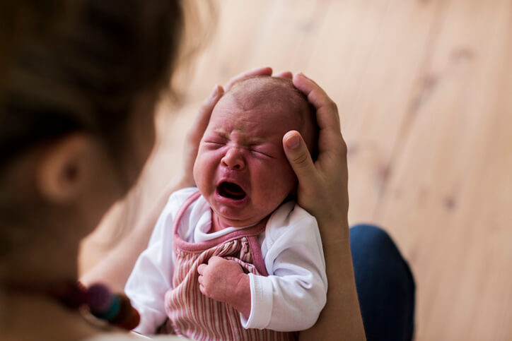 Unrecognizable mother holding crying newborn baby girl