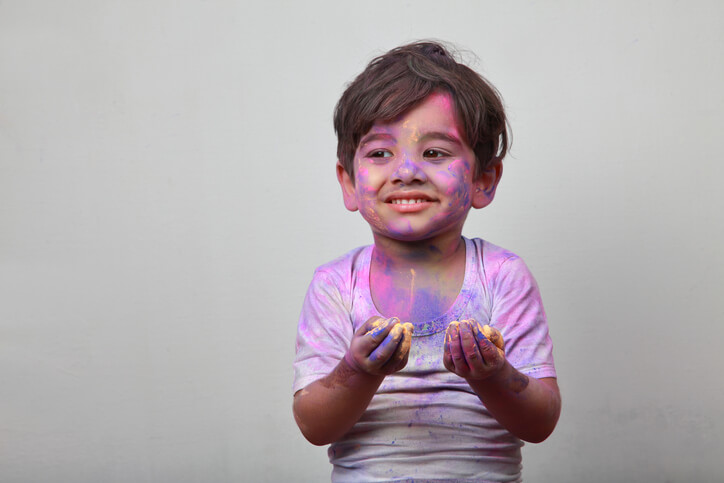 Little boy plays with Holi festival colours