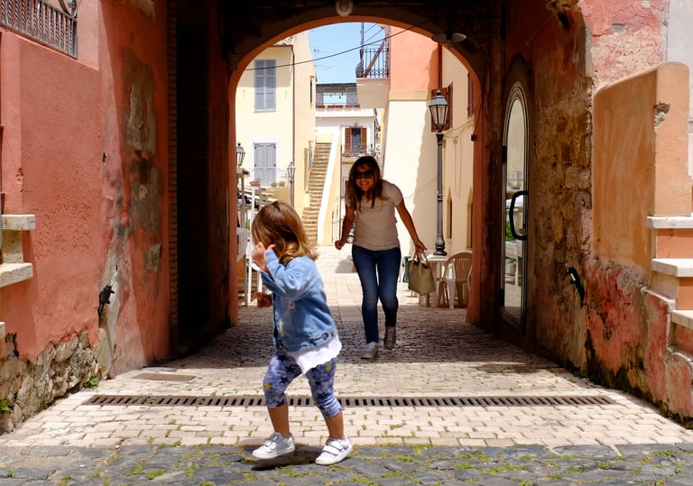 Little girl plays with her mother in a small and characteristic Italian village