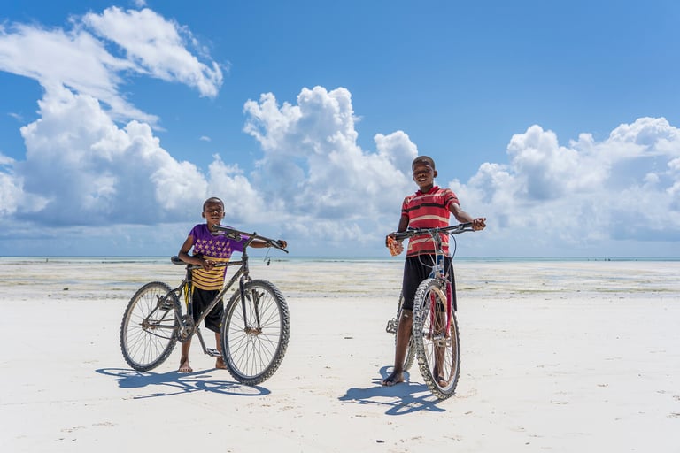 Unknown boys with a bicycle on a sandy beach at low tide on the island of Zanzibar, Tanzania