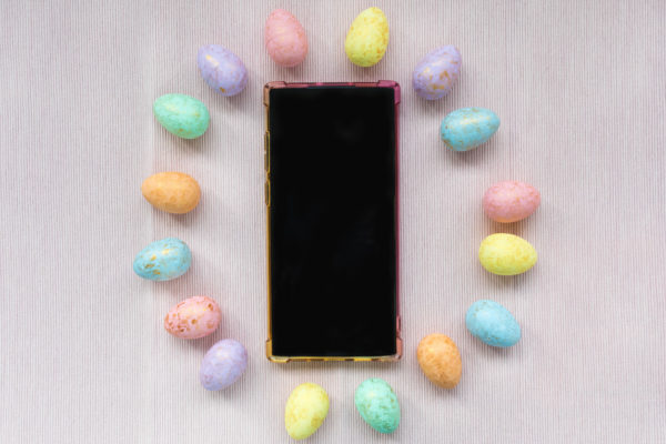 Eggs decoration and smartphone on pink background