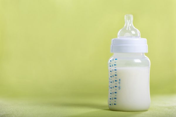 Baby bottle with milk on a green sheet