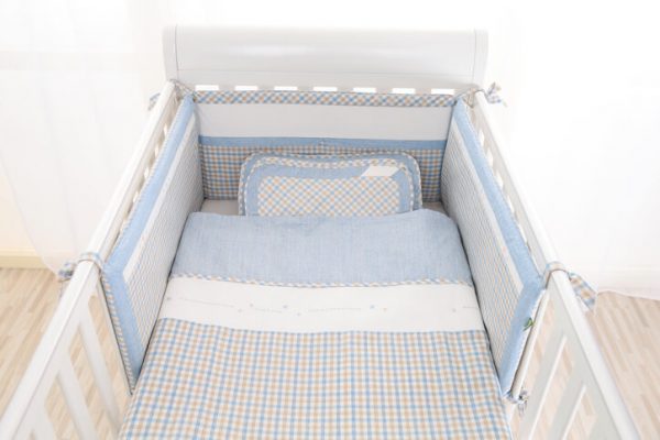 Cozy baby cot with white square pillows and patchwork comforter blanket