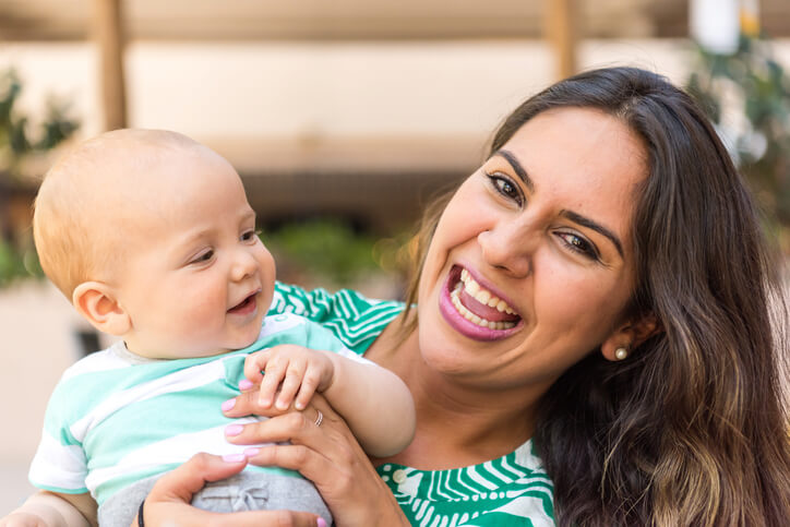 Smiling young hispanic woman posing with her baby
