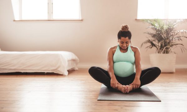 Beautiful expectant mother doing yoga at home