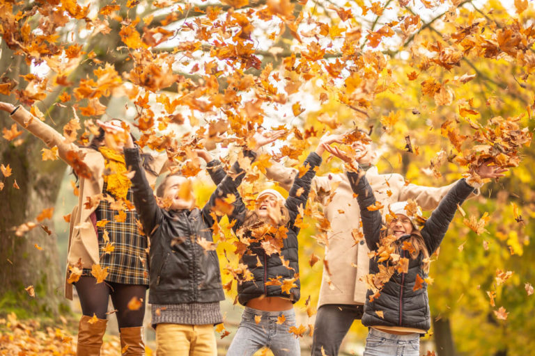 Family fun outdoors in the autumn by throwing fallen leaves up in the air