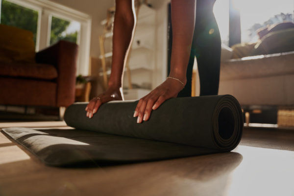 Closeup of hands of young pregnant woman folding fitness mat after working out at home