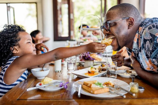 a young toddler feeding her dad at brunch for fathers day