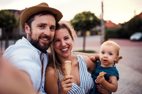 Parents and small toddler girl with ice cream outdoors in summer, taking selfie