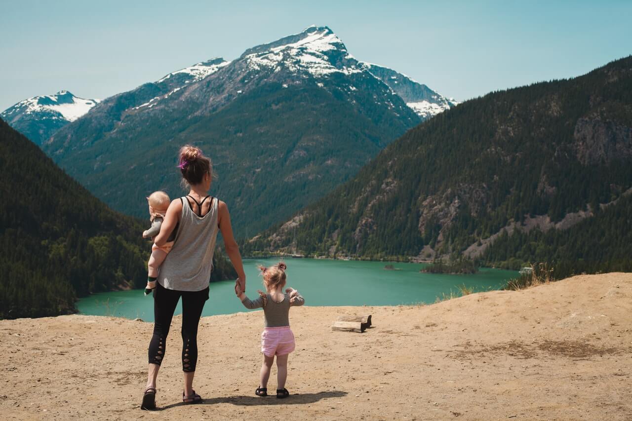 a mother holding her two kids while admiring a mountain view on vacation
