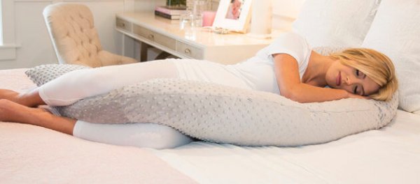 a pregnant woman lying on a pregnancy pillow