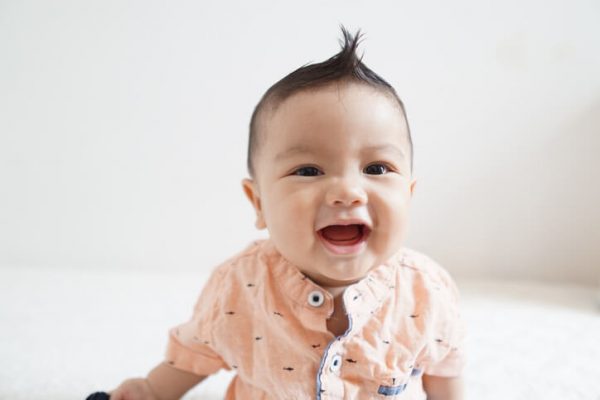 smiling baby boy with a mohawk style haircut