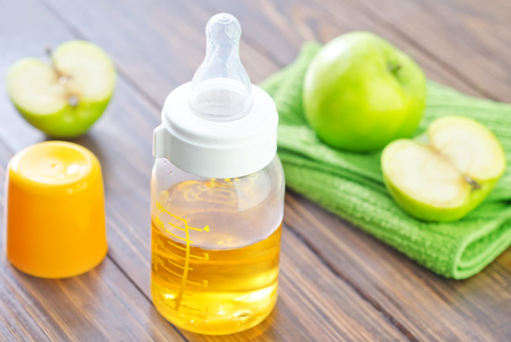 a baby's bottle filled with apple juice