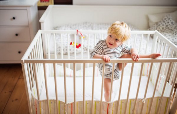 a toddler trying to climb out of his crib
