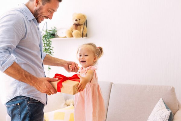 Excited girl holding her present with dad