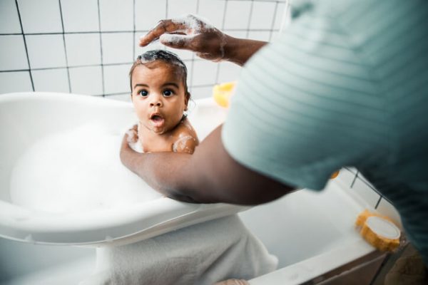 Loving father washing hair of his adorable newborn daughter