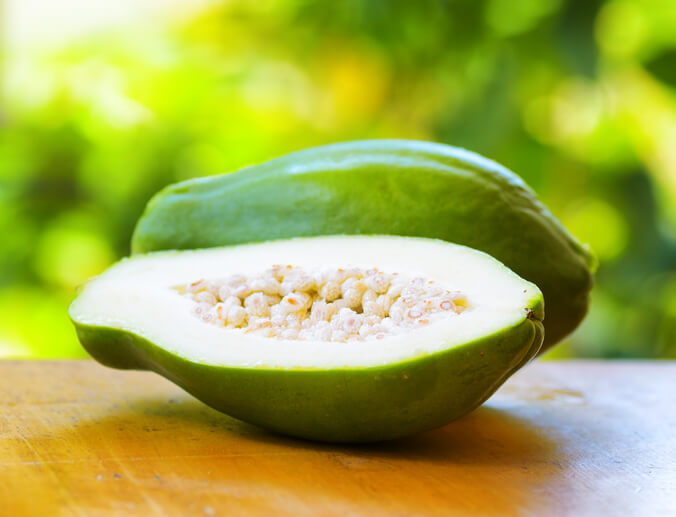 a green papaya sliced in half, papaya helps women to increase their breast milk supply