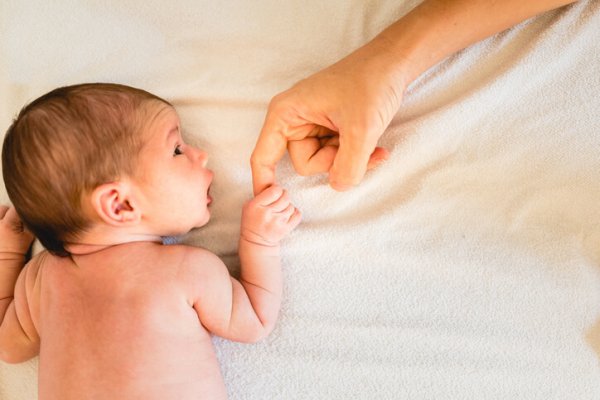 Newborn baby securely grasping his mother's hands