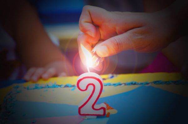 Hand with a lighter about to fire a two years birthday candle