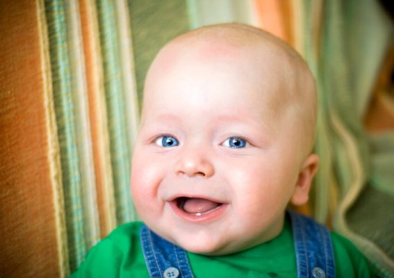 Top view of infant baby girl, smiling with his first two teeth