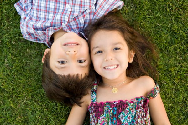 Two young siblings lying on the grass smiling together