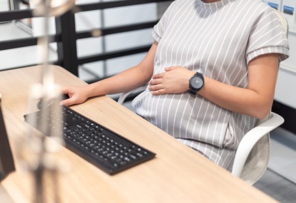 Pregnant woman is working on computer laptop and mobile phone