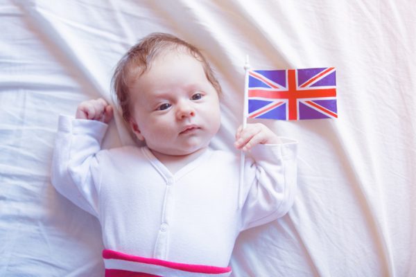 a little newborn baby holding a British flag