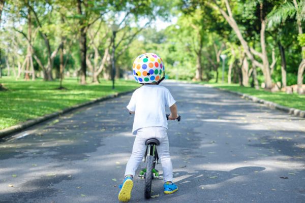 Backside of cute Asian 2 years toddler boy child wearing safety helmet learning to ride