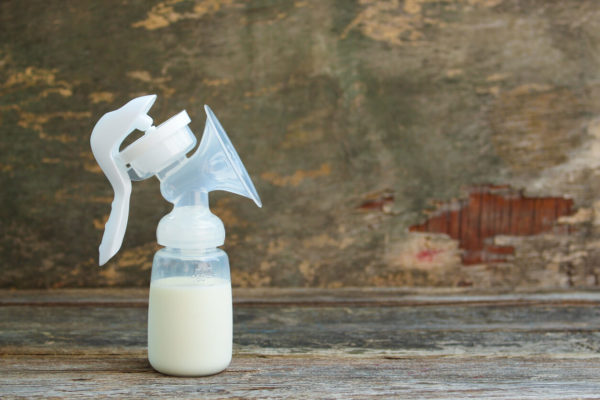 Breast pump of milk on wooden background
