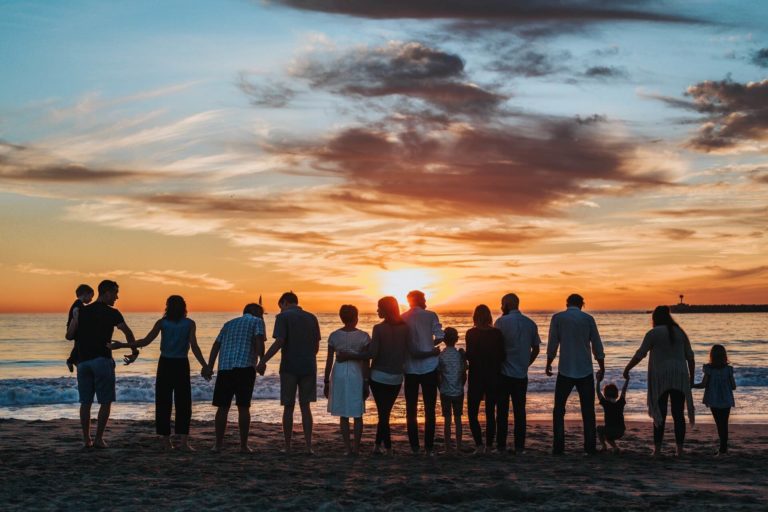 a large family watching the sunset on a beach
