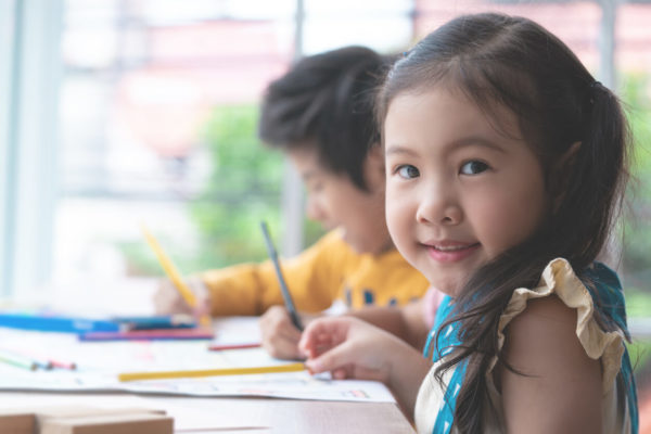 Asian girl is drawing in kindergarten art classroom