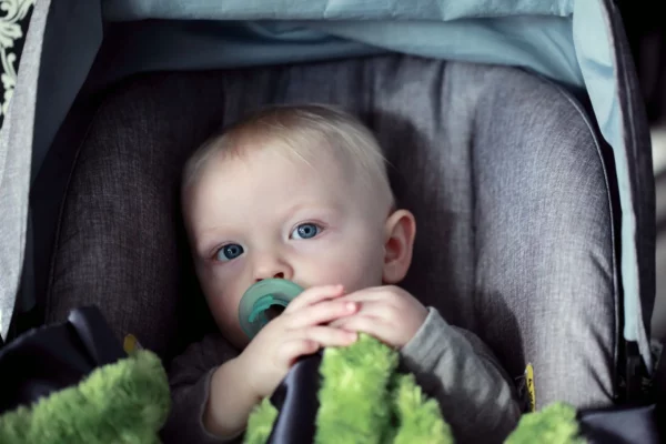 a baby sitting in a stroller with a pacifier in his mouth